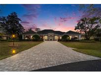 Stately home featuring a long brick driveway and lush landscaping, captured during a beautiful sunset at 8510 Kentucky Derby Dr, Odessa, FL 33556