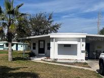 White one-story home with a black door and minimal landscaping and palm tree in the front yard at 105 Lake Tarpon Dr # 26, Palm Harbor, FL 34684