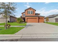 Inviting two-story home features a three-car garage, arched entryway, and well-manicured lawn at 11804 Bluegrass Field Ct, Riverview, FL 33579