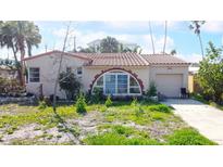 A charming bungalow with a red tile roof, unique arched window and attached garage at 15732 1St E St, Redington Beach, FL 33708