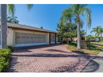 Charming home featuring a brick driveway, attached garage, and well-manicured landscaping at 2609 Locksley St, Sun City Center, FL 33573