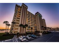 Stunning exterior view of a waterfront condo building with palm trees and parking at sunset at 4525 Cove Cir # 805, St Petersburg, FL 33708