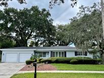 Charming single-story home featuring mature trees, a well-maintained lawn, and an attached two-car garage at 4802 W San Jose St, Tampa, FL 33629