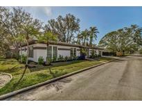 Charming exterior featuring well-maintained landscaping, mature trees, and a neatly paved driveway at 525 Lamara Ne Way, St Petersburg, FL 33704