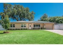 Charming single-story home featuring a lush green lawn, mature trees, and a welcoming front entrance at 9838 53Rd N Ave, St Petersburg, FL 33708