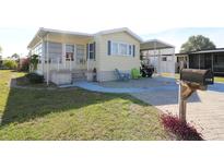 Charming home featuring light yellow siding, blue shutters, and a brick foundation with an inviting front yard at 114 W Saint Johns Way, Apollo Beach, FL 33572