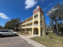 Three-story condo building featuring balconies, a brick tower, and a well-maintained lawn and parking at 2226 Switzerland Way # 52, Clearwater, FL 33763