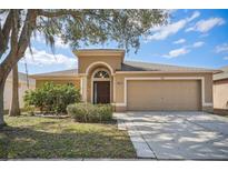 Inviting single-story home featuring a two-car garage, well-manicured landscaping, and a classic arched entryway at 2811 Butterfly Landing Dr, Land O Lakes, FL 34638