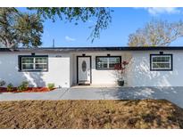 Charming single-story home featuring a modern white exterior, dark trim and a well maintained lawn at 4716 Eldorado Dr, Tampa, FL 33615