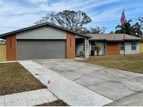 Charming single-story home with a gray and brown exterior, featuring a two-car garage and a well-manicured lawn at 7281 Channelside N Ln, Pinellas Park, FL 33781