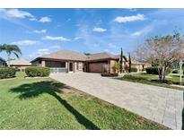 Charming single-story home with brick driveway, well-manicured landscaping, and a welcoming screened in porch at 1228 Caloosa Creek Ct, Sun City Center, FL 33573