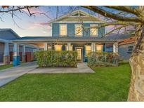 Charming blue two-story home with covered porch, manicured lawn, and mature hedges at 1920 E Idlewild Ave, Tampa, FL 33610