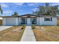 White brick ranch house with gray accents, landscaped yard, and walkway at 2904 Matchlock Dr, Holiday, FL 34690