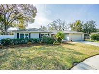 Charming single-story home featuring a lush front lawn, flowering bushes, and a two-car garage at 3704 Thornwood Pl, Tampa, FL 33618