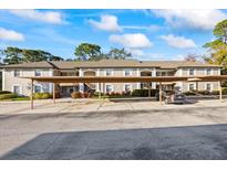 Condo building exterior showing the carports, second story, neutral paint, and manicured landscaping at 5265 E Bay Dr # 424, Clearwater, FL 33764