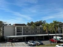 Condominium building exterior featuring balconies and covered parking in a tropical setting at 860 Virginia St # 303, Dunedin, FL 34698