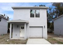 Two-story home featuring a garage, white door, and a modern, gray stucco exterior at 2222 E Emma Street, Tampa, FL 33610