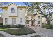 Two-story home with brick driveway, manicured lawn, and a large tree on a sunny day at 4610 W Browning Ave, Tampa, FL 33629