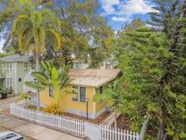 Charming cottage-style home with yellow siding, mature landscaping and white picket fence at 1045 6Th N St, St Petersburg, FL 33701