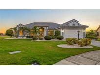 Beautiful single-story home featuring lush landscaping, a gray roof, and well-maintained lawn at 2011 Captiva Ct, Sun City Center, FL 33573