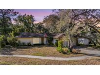 Charming single-story home featuring stone accents, mature trees, and an American flag at 421 Wayfarer Ct, Tarpon Springs, FL 34689