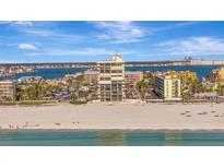 Beautiful exterior view of a beachfront building on a sunny day with cars and pedestrians in the foreground at 5396 Gulf Blvd # 904, St Pete Beach, FL 33706