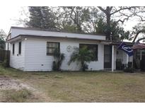 Charming single-story home with white siding and a cozy front porch, enhanced by flags and small palm trees at 10554 116Th N Ave, Largo, FL 33773