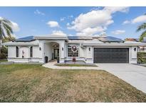 Charming home featuring solar panels, a dark garage door, and impeccable landscaping at 1123 Hounds Run, Safety Harbor, FL 34695
