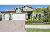 Charming home with a well-manicured lawn, a two-car garage, and a beautiful red brick driveway at 624 Maraviya Blvd, Nokomis, FL 34275