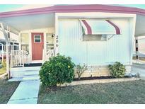 Charming single-story home featuring a covered front porch, white siding, and well-maintained landscaping at 9790 66Th N St # 206, Pinellas Park, FL 33782