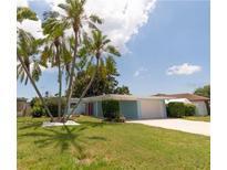 Charming single-story home with manicured lawn, mature palm trees and a light blue exterior at 10828 99Th Pl, Seminole, FL 33772