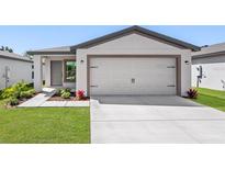 Modern home featuring a two car garage, a well-maintained lawn, and tasteful landscaping at 11275 Old Squaw Rd, Weeki Wachee, FL 34614