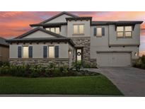 Two-story home with stone accents, neutral siding, shutters, manicured lawn, and a two-car garage at 12829 Tortoise Shell Pl, Riverview, FL 33579