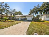 Charming one-story home featuring a manicured front yard and a paved driveway leading to an attached garage at 2008 Harvard Ave, Dunedin, FL 34698