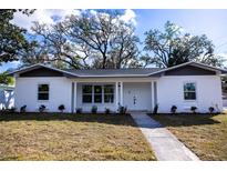 Charming single-story home with a white brick facade, gray trim, and a well-manicured lawn under a bright sky at 3401 E Hanna Ave, Tampa, FL 33610