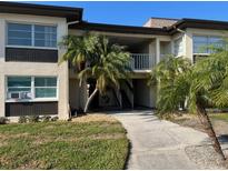 Condo building featuring lush landscaping with stone accents, palm trees and a walkway leading to the entrance at 4715 Jasper Dr # 208, New Port Richey, FL 34652