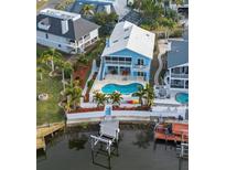 Bright blue two-story waterfront home with a private pool and dock and luscious tropical landscaping at 6029 Bayway Ct, New Port Richey, FL 34652