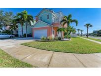 Charming two-story home with a manicured lawn, a two-car garage, and lush palm trees, perfect for a Gathering at 6571 Simone Shores Cir, Apollo Beach, FL 33572