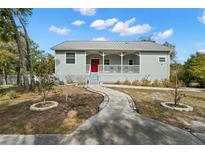 Charming single-story home with a metal roof, inviting front porch, and vibrant red front door at 6131 Central Ave, New Port Richey, FL 34653