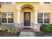 Charming home featuring a covered front door with decorative pillars and manicured landscaping at 6262 Maisie Rd, Zephyrhills, FL 33542