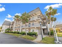 Well-maintained condo building with lush landscaping and palm trees under a bright blue sky at 716 Cordova Grn, Seminole, FL 33777