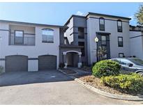 Condo exterior with two-tone paint, two garage doors, and an arched entryway at 8517 Sea Harbour Ln # 103, Temple Terrace, FL 33637