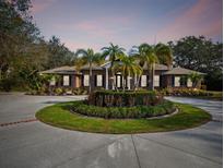 Stunning brick home boasts a circular driveway with lush palm trees and meticulously maintained landscaping at 9606 Braden Run, Bradenton, FL 34202