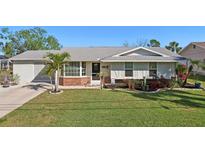 Charming single-story home features a well-manicured lawn, palm trees, and decorative flowerbeds at 18350 Burkholder Cir, Port Charlotte, FL 33948