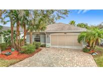 Charming single-story home features a paver driveway, tropical landscaping, and a neutral color scheme at 29523 Waggle Dr, San Antonio, FL 33576