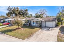 Charming single-story home featuring a well-manicured lawn and a long driveway, perfect for parking at 3624 Wiltshire Dr, Holiday, FL 34691