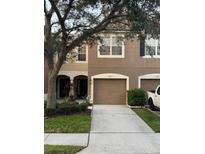 Townhouse showcasing a two-car garage, neutral-colored facade, and well-manicured landscaping at 4915 Pond Ridge Dr, Riverview, FL 33578