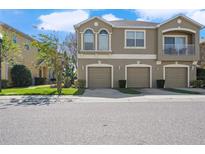 Two story townhome featuring a three car garage and an open balcony at 8835 Moonlit Meadows Loop, Riverview, FL 33578