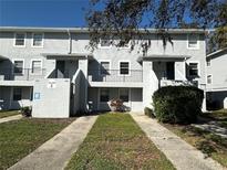 View of the townhouse with a lawn area and sidewalks leading to the front doors with the building number on the exterior wall at 7129 E Bank Dr # 7129, Tampa, FL 33617