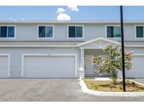 New townhouse exterior featuring a one-car garage, white trim, and a blooming decorative tree at 7529 62Nd N Way, Pinellas Park, FL 33781